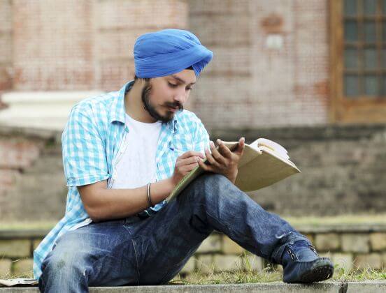 Man wearing blue turban, making notes in notebook